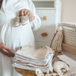 خانم باردار با لباس سفید و کفش کودک در دستش