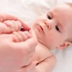 آشنایی با علائم اوتیسم در سه ماه اول تولد کودکی که دستان مادرش را گرفته و نگاه می کند.