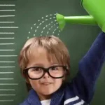 پسر بچه ای که عینک دارد و دارد با آب پاش روی کله اش آب می ریزد.